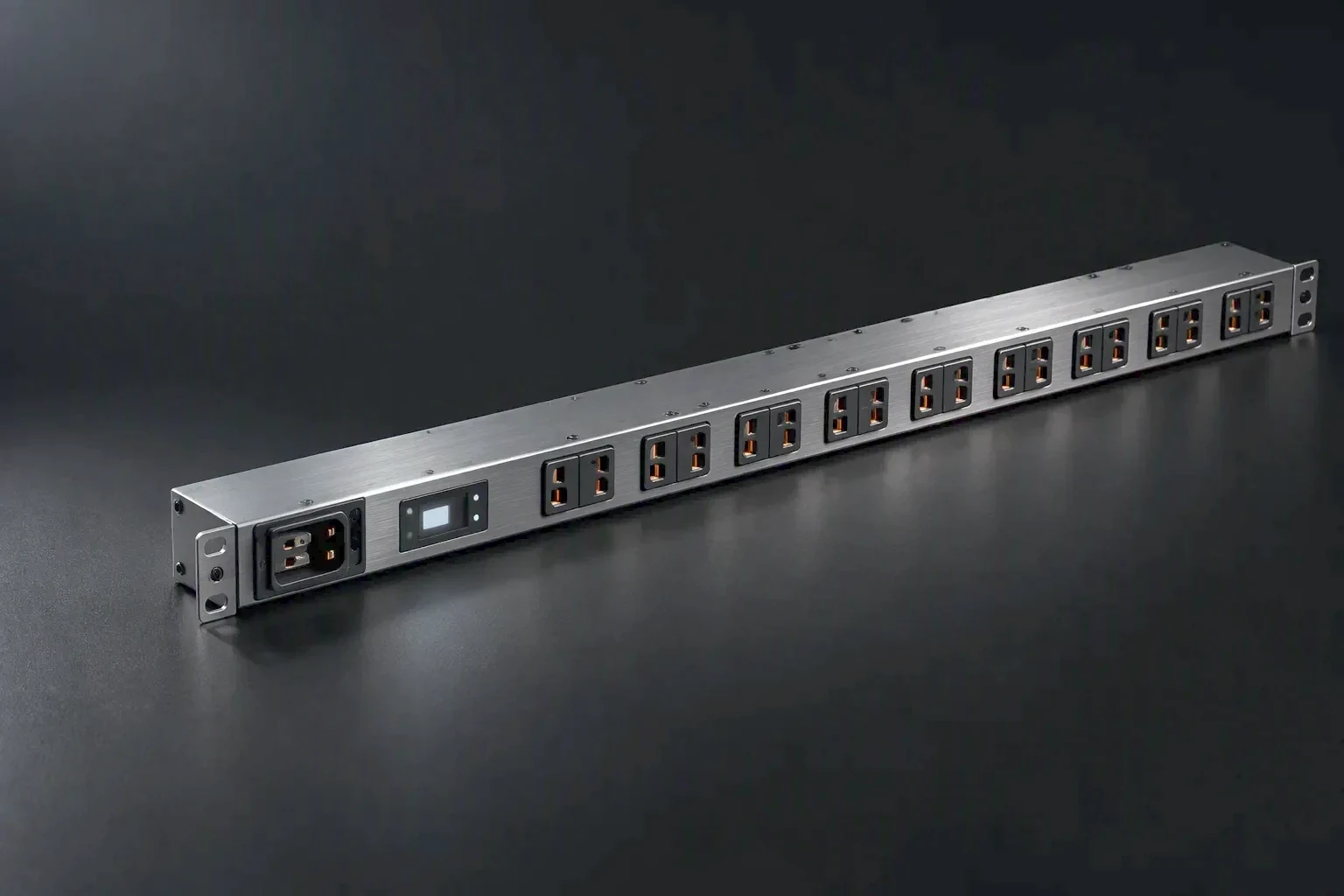 A completed rack PDU on a dark bench before packing, its brushed chassis and outlet row lit by one raking light from the left
