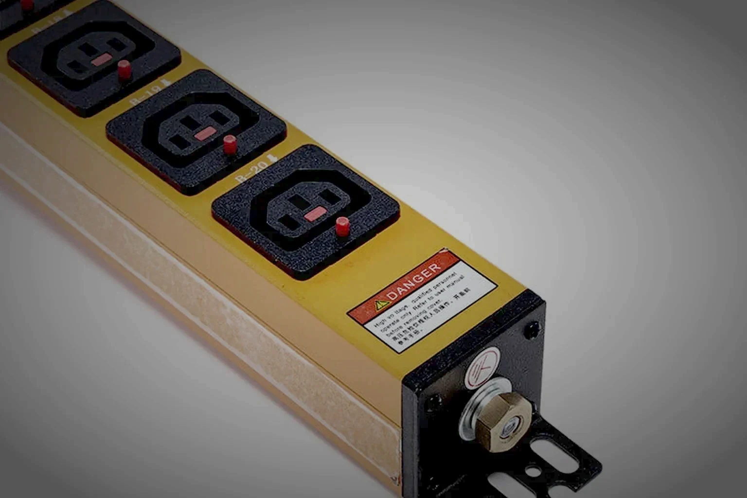 A shared equipment cabinet in a colocation hall, the rack PDU visible at the open rack edge and lit by one raking light