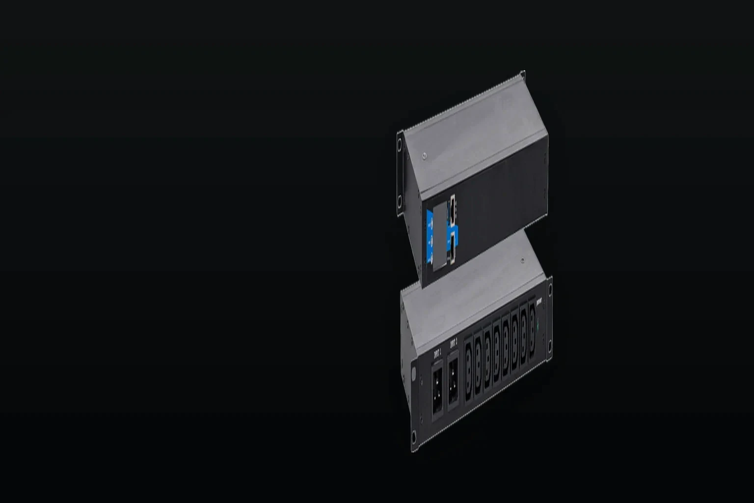 A rack PDU photographed from a raised three-quarter angle, one raking light along the brushed steel face so the chassis depth and the outlet row read as one continuous line, the unit held in the right of the frame and the left side falling into unlit dark