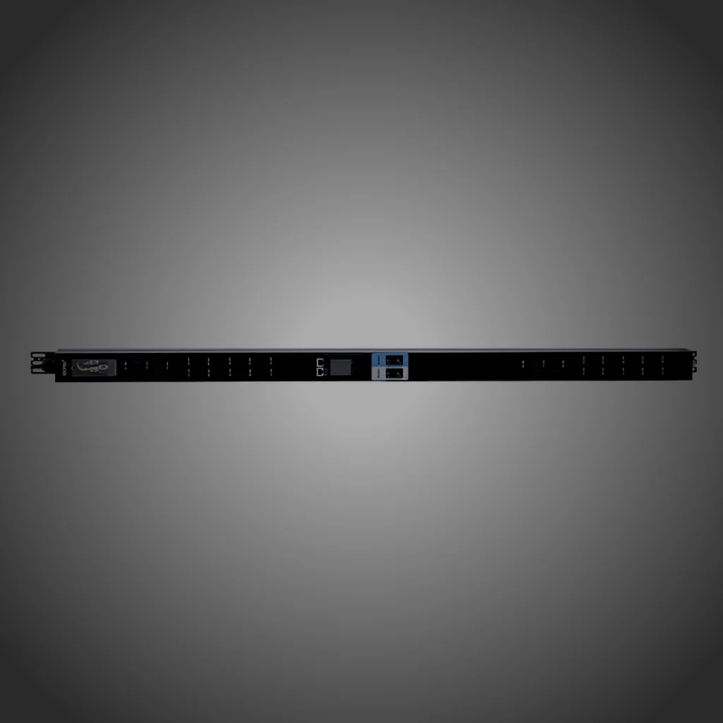 Macro of a rack PDU readout panel inside a dark equipment aisle, the small OLED screen glowing with white metering glyphs and the brushed steel face falling away into shadow on the left