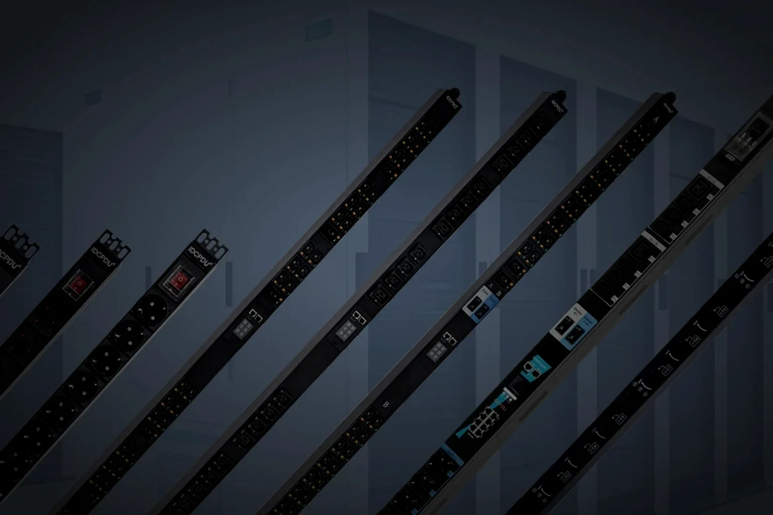 A horizontal 1U rack PDU photographed from a raised three-quarter angle with the outlet row running across the front face and the OLED panel at its left end, the unit held in the right of the frame and the left side in unlit dark